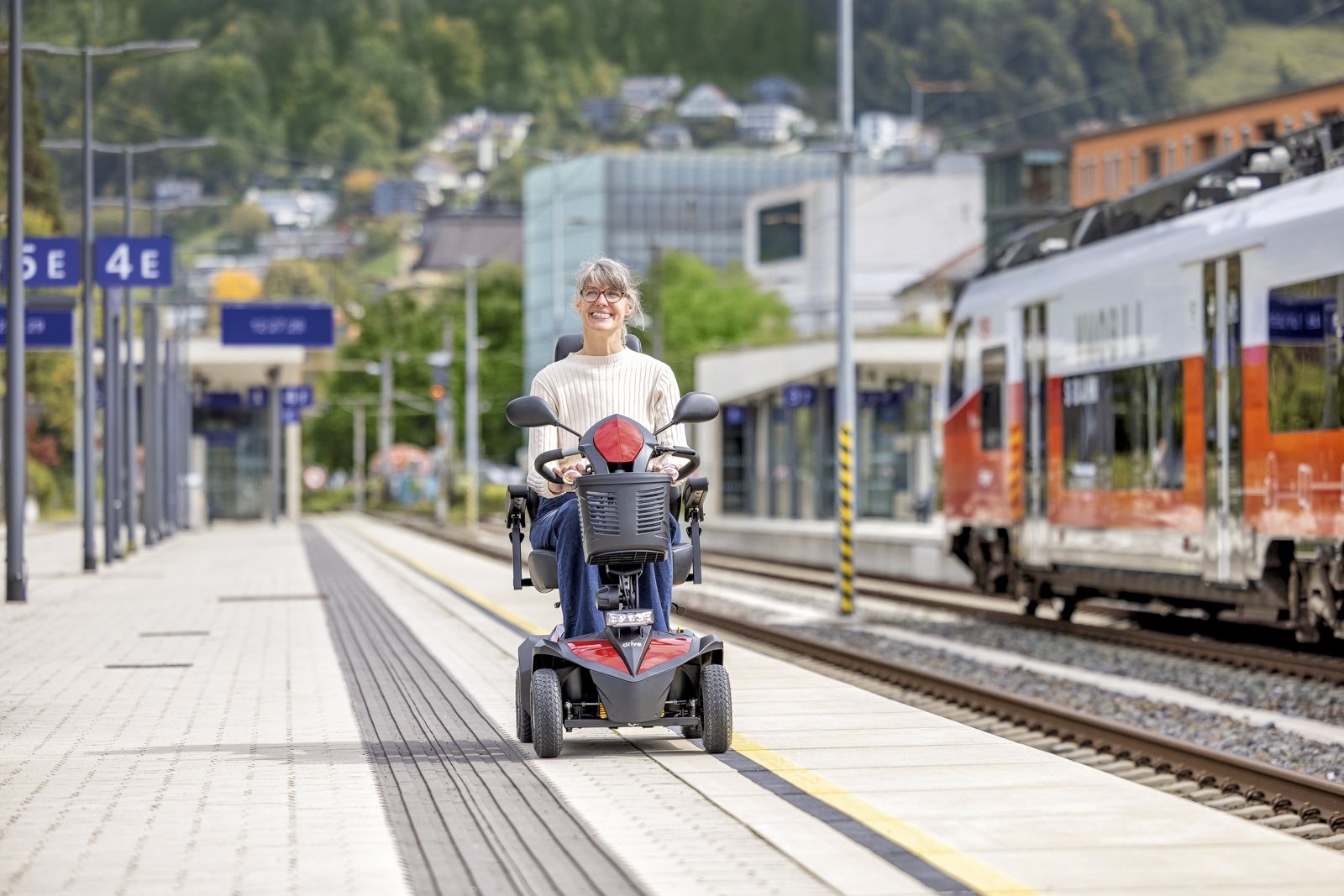 Frau mit Elektromobil am Bahnhof Frau mit einem Elektromobil auf einem Bahnsteig