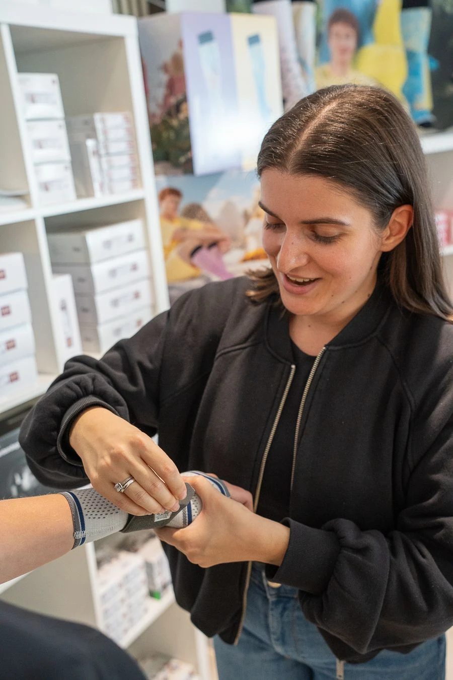 Eine Mitarbeiterin passt einer Kundin eine Handgelenkbandage an